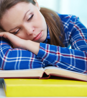 Tired student sleeping over textbooks